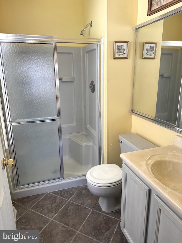 full bath with vanity, tile patterned flooring, a shower stall, and toilet