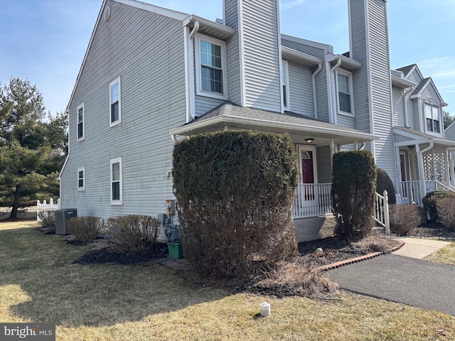 view of front of property featuring a porch, central AC, a chimney, and a front lawn