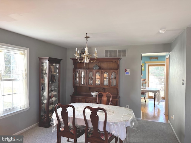 dining space featuring carpet floors, visible vents, baseboards, and an inviting chandelier