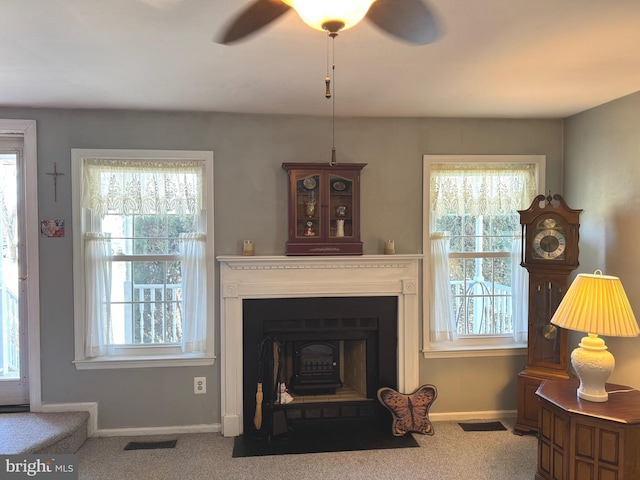 carpeted living area featuring a fireplace with flush hearth, a wealth of natural light, baseboards, and a ceiling fan