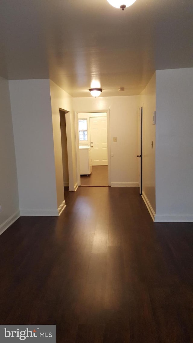 empty room with baseboards and dark wood-type flooring