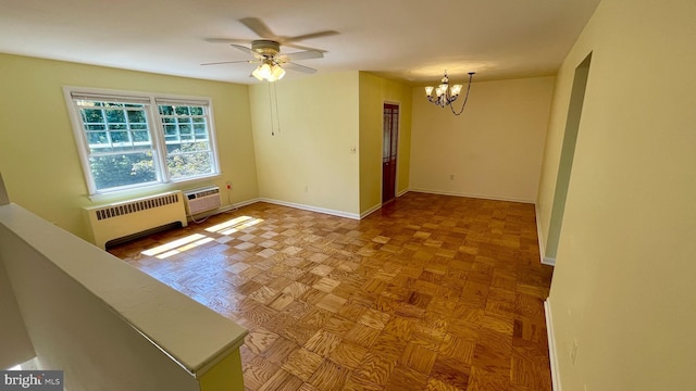 empty room with baseboards, a wall unit AC, radiator heating unit, and ceiling fan with notable chandelier