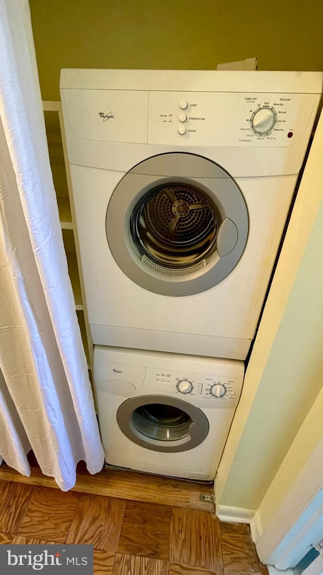 laundry area featuring stacked washer and dryer, laundry area, and wood finished floors