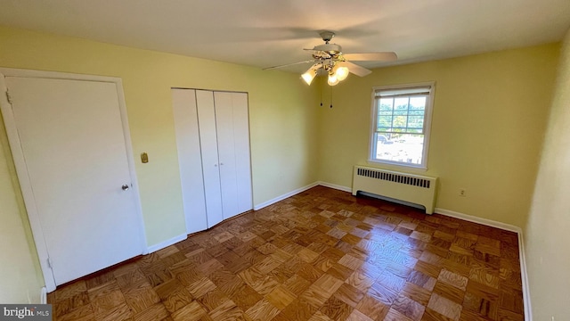 unfurnished bedroom featuring radiator, baseboards, and a ceiling fan