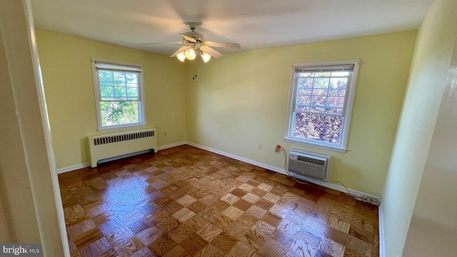 spare room featuring baseboards, an AC wall unit, ceiling fan, and radiator