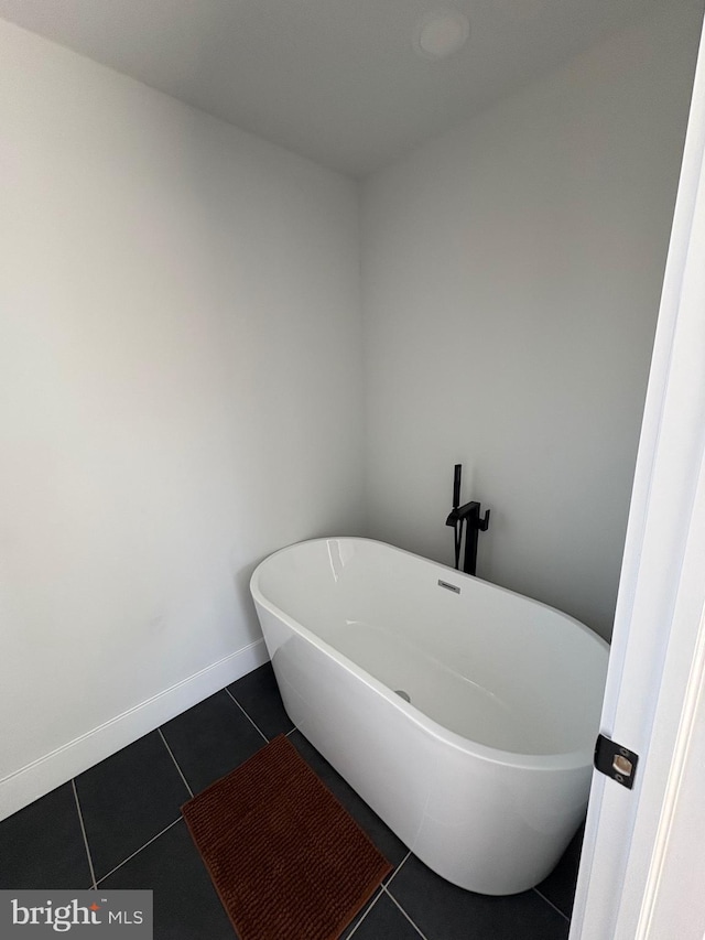 full bath with baseboards, a freestanding tub, and tile patterned floors