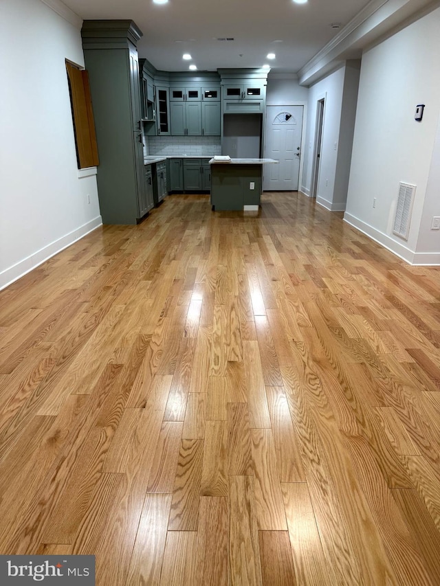 kitchen with light wood-style flooring, visible vents, decorative backsplash, and crown molding