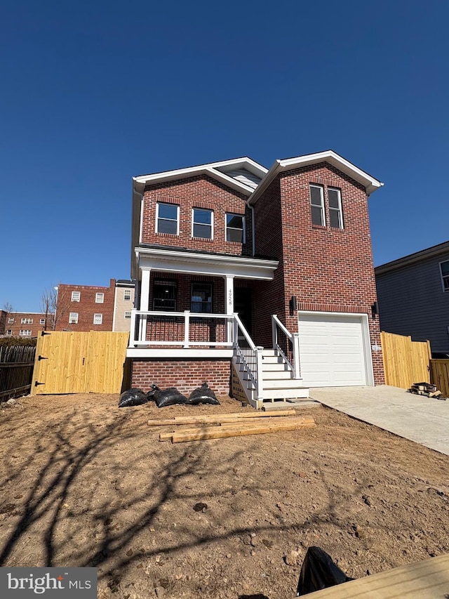 traditional-style home with brick siding, a porch, an attached garage, fence, and driveway