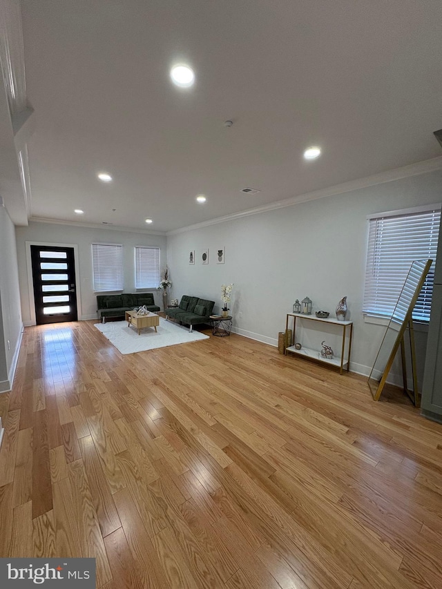 interior space with light wood-style floors, crown molding, and baseboards