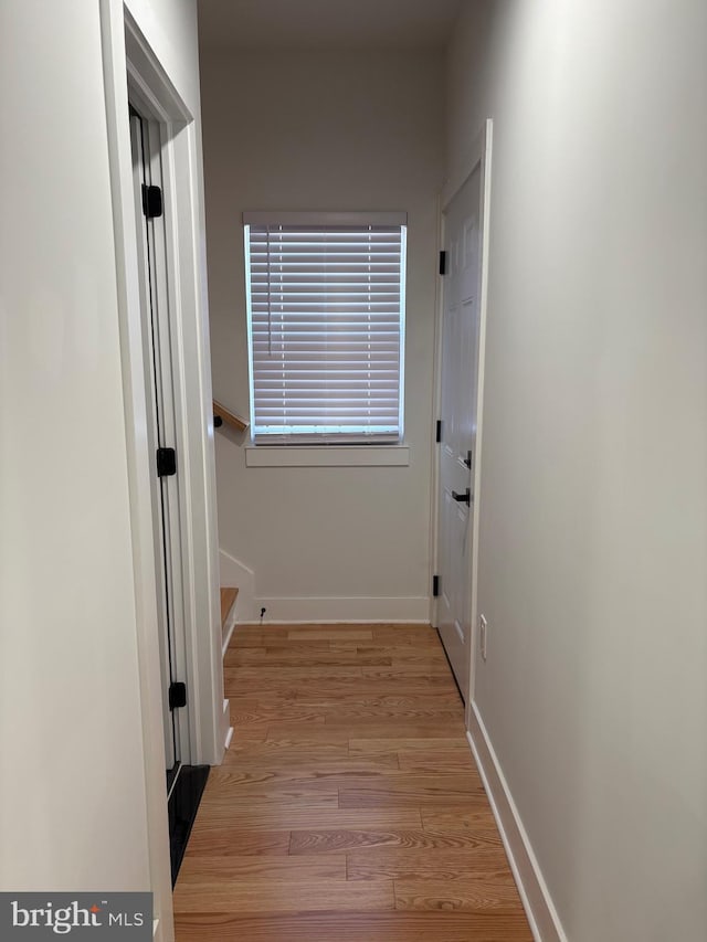 corridor featuring baseboards and light wood finished floors