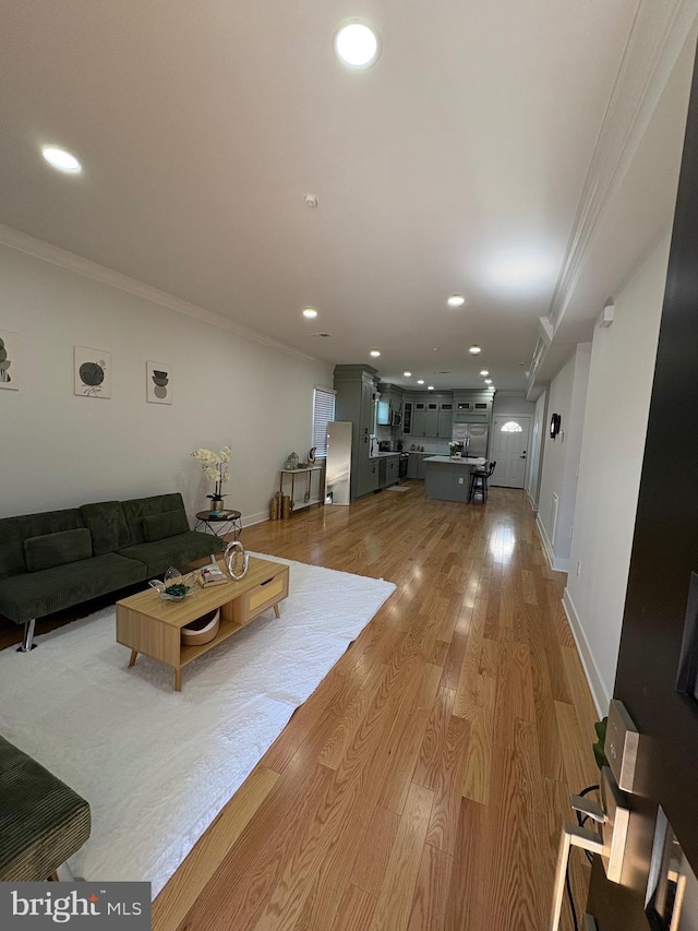 living room with light wood-type flooring, crown molding, baseboards, and recessed lighting