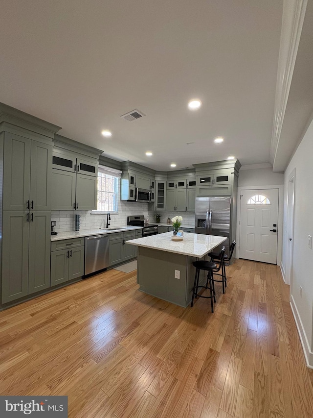 kitchen featuring visible vents, a sink, stainless steel appliances, light wood-type flooring, and backsplash