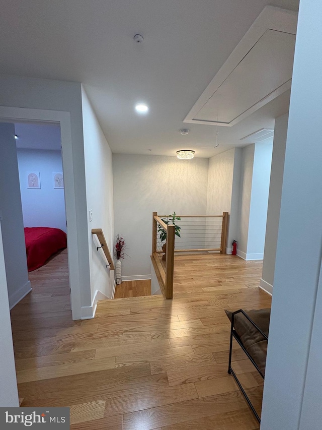 corridor featuring attic access, baseboards, an upstairs landing, and wood finished floors