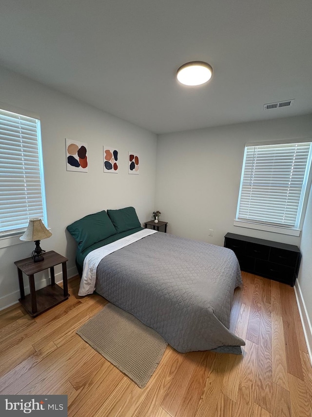 bedroom with visible vents, baseboards, and wood finished floors