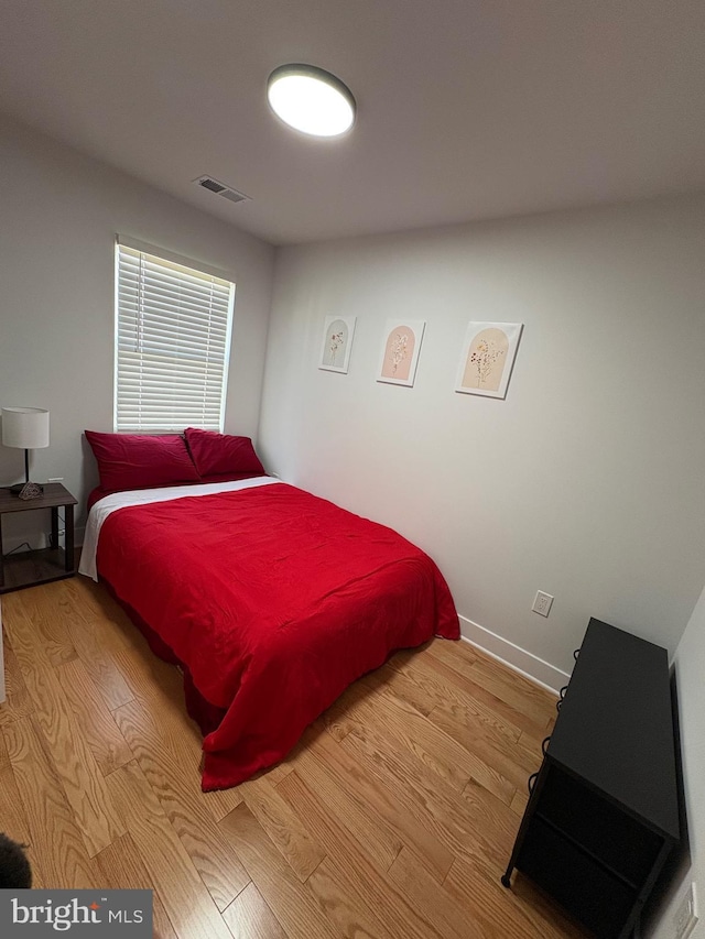 bedroom featuring baseboards, visible vents, and wood finished floors