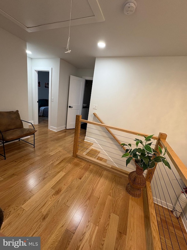 interior space with light wood-style floors, attic access, baseboards, and an upstairs landing