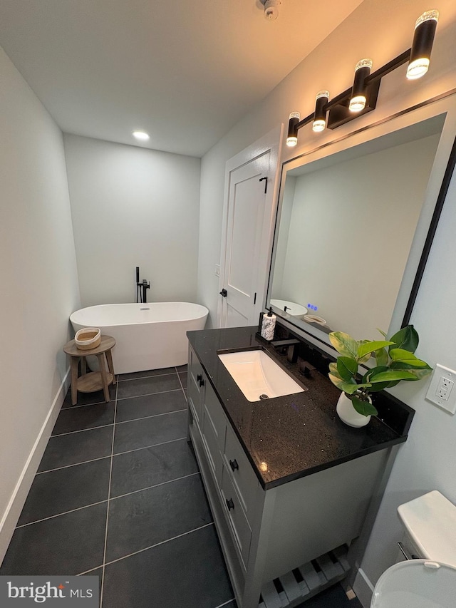 bathroom featuring baseboards, toilet, a soaking tub, tile patterned flooring, and vanity