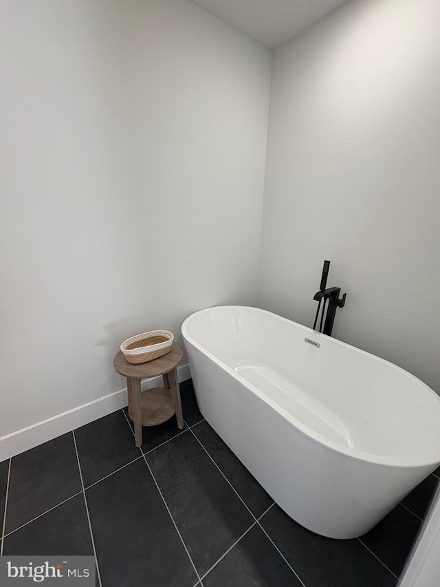 bathroom featuring a soaking tub, baseboards, and tile patterned floors