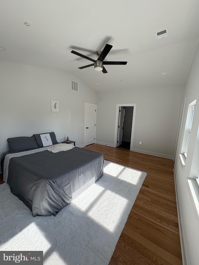 bedroom with a ceiling fan, lofted ceiling, visible vents, and wood finished floors