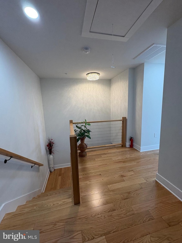 interior space featuring attic access, baseboards, and wood finished floors