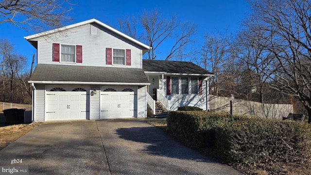 tri-level home with a garage, concrete driveway, and fence