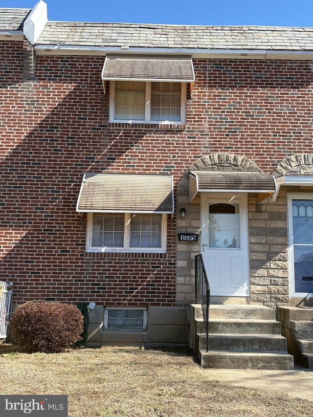 view of front facade featuring stone siding, a high end roof, and brick siding