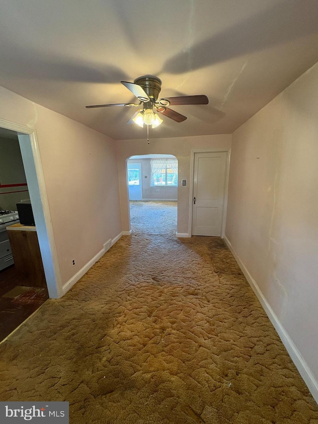 hallway with carpet floors, arched walkways, and baseboards