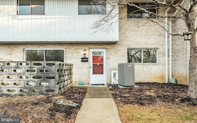 entrance to property featuring central AC and brick siding