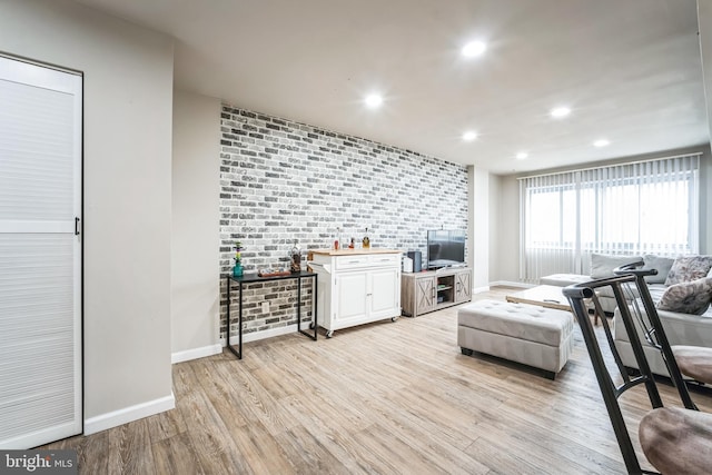 living room featuring recessed lighting, light wood-style flooring, brick wall, and baseboards