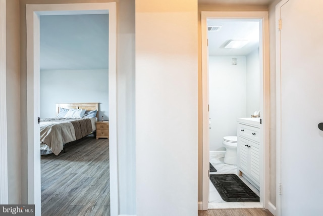 ensuite bathroom with ensuite bath, toilet, wood finished floors, and visible vents