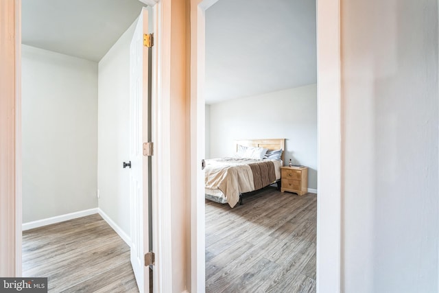 corridor featuring baseboards and wood finished floors