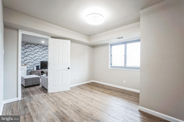 unfurnished bedroom with wood finished floors, visible vents, and baseboards