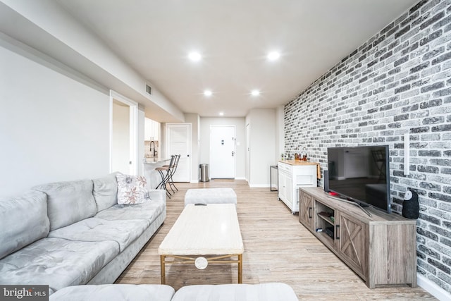 living room featuring visible vents, brick wall, baseboards, light wood-type flooring, and recessed lighting