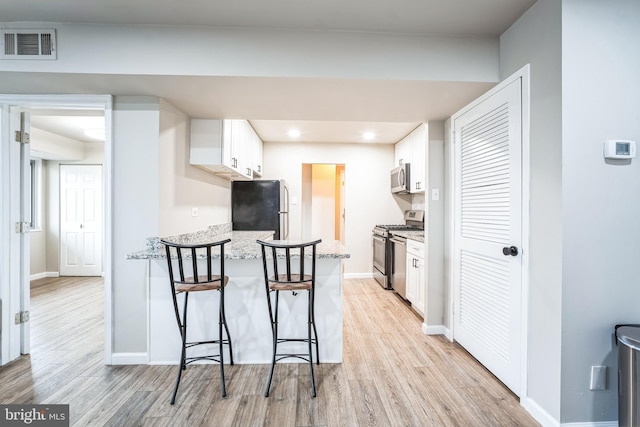 kitchen featuring white cabinetry, light wood-style flooring, and appliances with stainless steel finishes