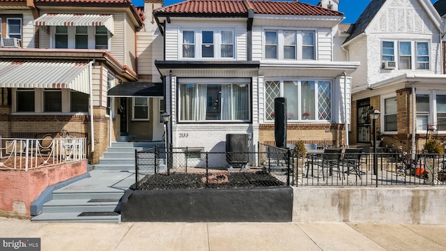 view of front of property featuring entry steps, cooling unit, brick siding, fence, and a tiled roof