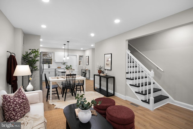 living area featuring recessed lighting, visible vents, baseboards, stairway, and light wood finished floors