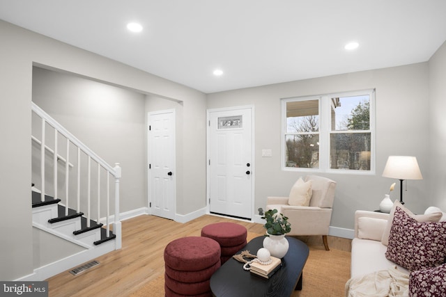 living room featuring baseboards, visible vents, stairway, wood finished floors, and recessed lighting