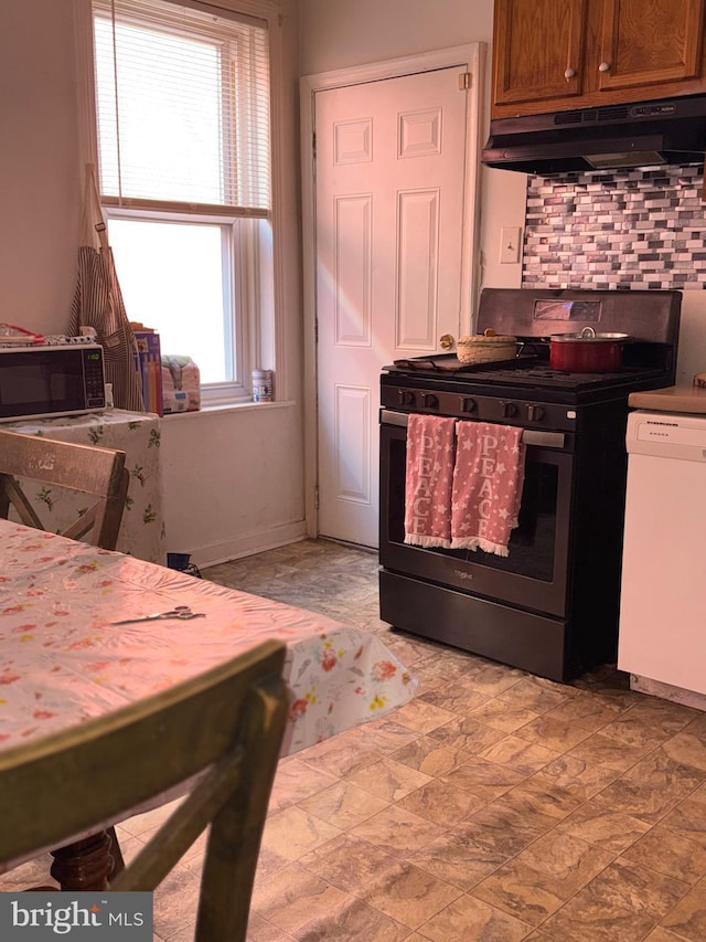 kitchen with brown cabinets, tasteful backsplash, gas range, dishwasher, and under cabinet range hood