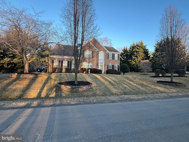 colonial home with a front lawn and brick siding