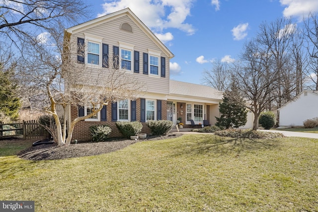 view of front of property featuring brick siding, a front yard, and fence