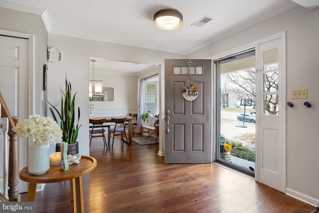 foyer with ornamental molding, visible vents, baseboards, and wood finished floors