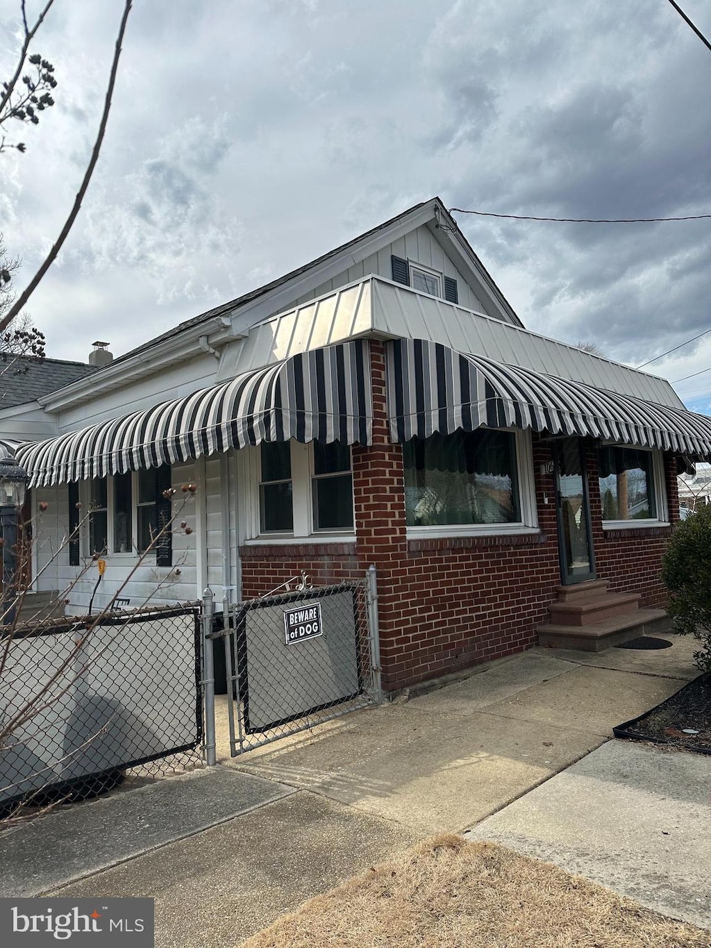 view of front of house featuring a gate, brick siding, and fence