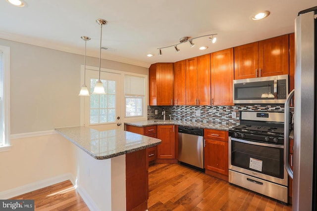 kitchen featuring a peninsula, appliances with stainless steel finishes, brown cabinets, and tasteful backsplash