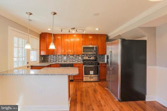 kitchen featuring wood finished floors, ornamental molding, appliances with stainless steel finishes, light stone countertops, and tasteful backsplash