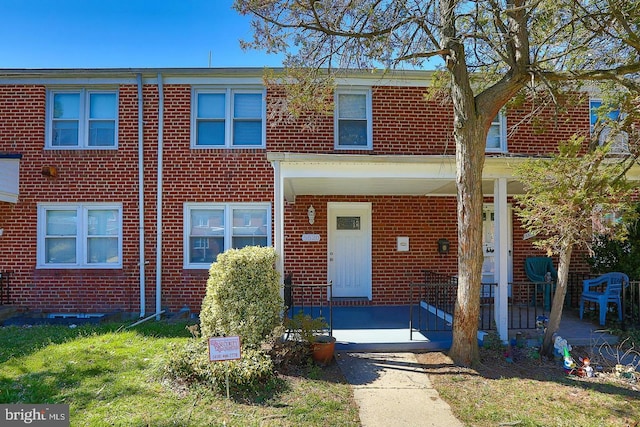 townhome / multi-family property with a porch and brick siding