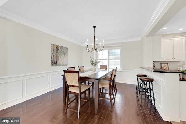 dining area featuring crown molding, a decorative wall, dark wood-style floors, and a chandelier