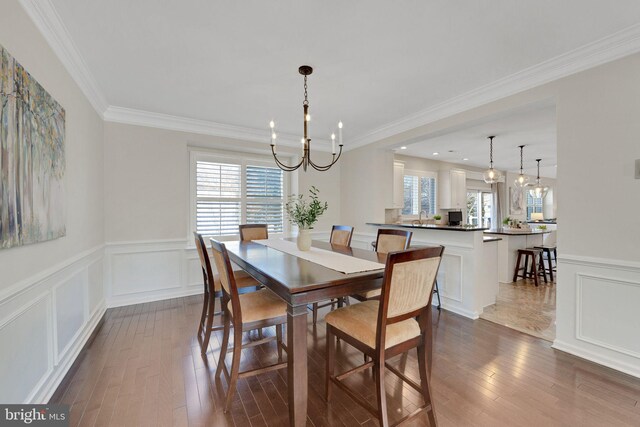 dining room with dark wood-style floors, a healthy amount of sunlight, a chandelier, and a decorative wall