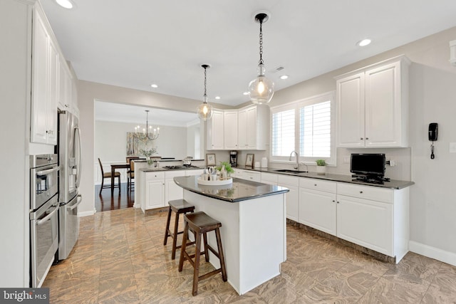 kitchen featuring a peninsula, a sink, white cabinets, appliances with stainless steel finishes, and dark countertops