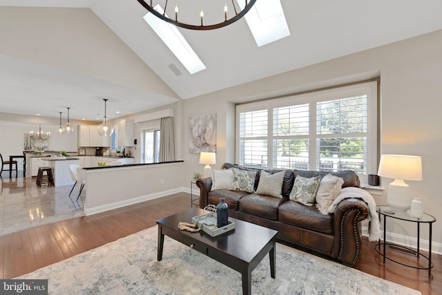 living area with a skylight, plenty of natural light, light wood-style flooring, and a chandelier