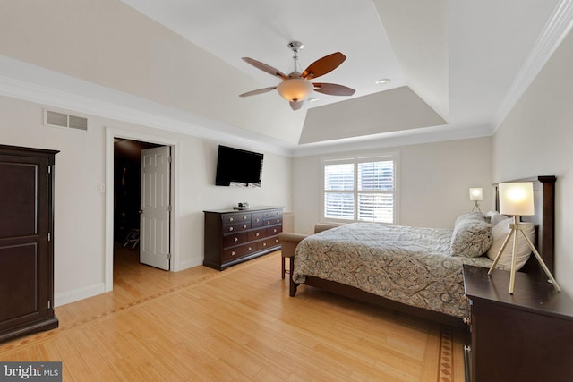 bedroom featuring visible vents, light wood finished floors, baseboards, crown molding, and a raised ceiling